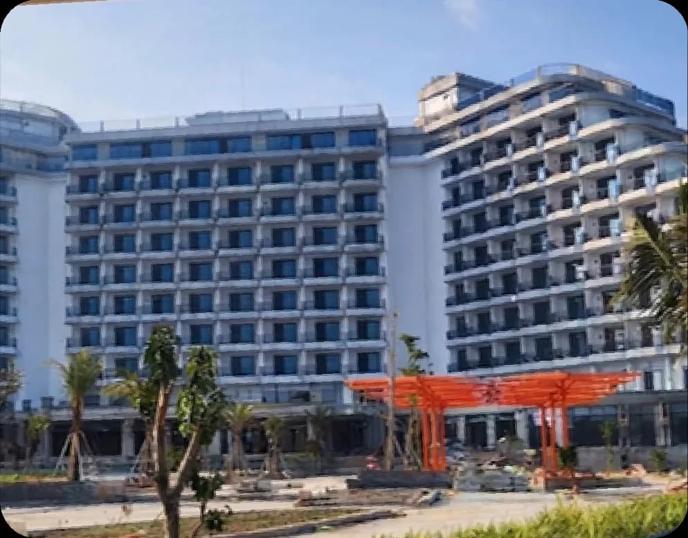 Khối nhà khách sạn Longbeach Móng Cái trong giai đoạn hoàn thiện sơn ngoại thất, mái che màu cam phía trước sảnh.